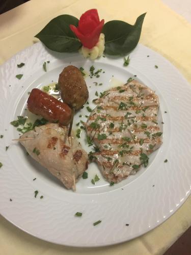 a white plate with meat and vegetables on a table at hotel lo sciatore in Cotronei