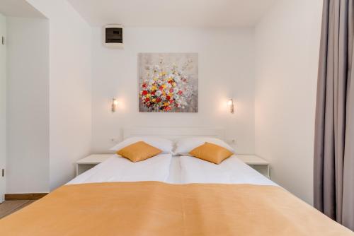 a bedroom with a bed with two pillows and a painting at Apartments Villa Tudor in Hvar