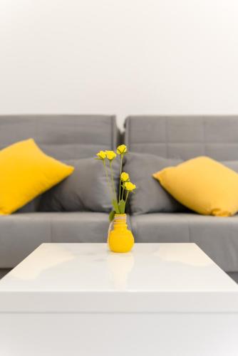 a yellow vase with yellow flowers on a table with a couch at Apartments Villa Tudor in Hvar