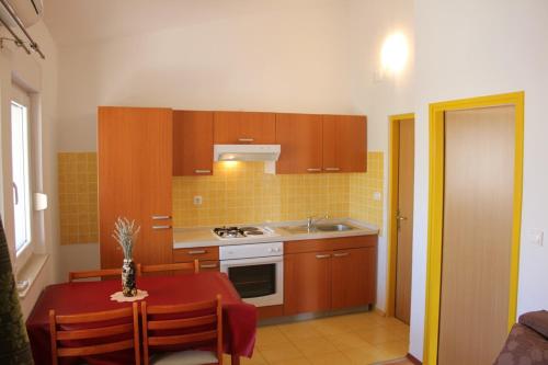 a kitchen with wooden cabinets and a table with a red table cloth at Apartments Ante - 50m from the sea in Posedarje