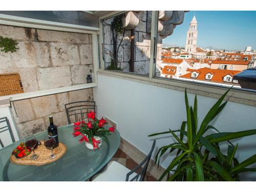 a table with flowers and a bottle of wine and a window at Riva Royal Lounge Apartment in Split