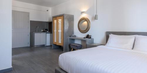 a bedroom with a white bed and a kitchen at Elitoz Suites in Oia