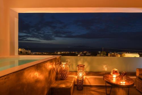 a balcony with a view of a pool at night at Elitoz Suites in Oia