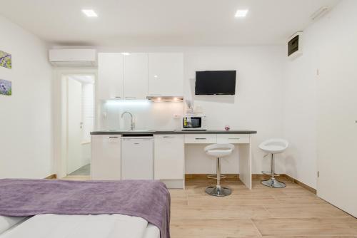 a kitchen with white cabinets and a counter with stools at Apartments Villa Tudor in Hvar