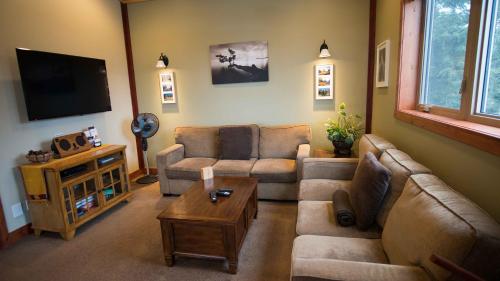 a living room with two couches and a flat screen tv at Cedar House Restaurant & Chalets in Golden