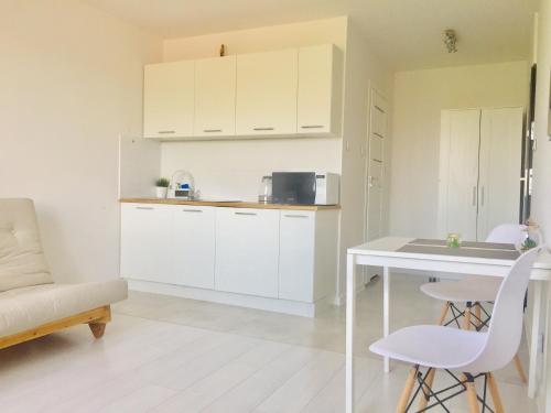 a kitchen with white cabinets and a table and chairs at Andersena 190 B - 12 piętro - 10 min CMKP - 5 min Metro - 15 min Centrum in Warsaw