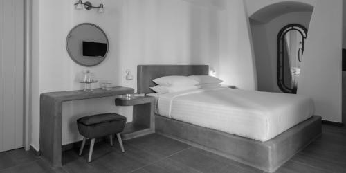 a bedroom with a bed and a mirror and a stool at Elitoz Suites in Oia