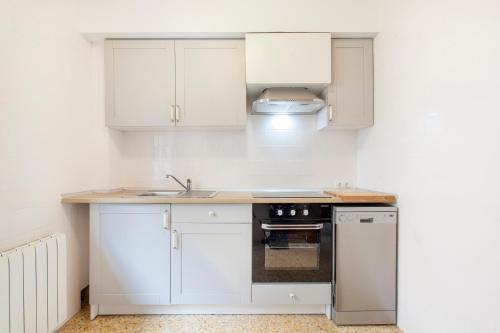 a kitchen with white cabinets and a sink and a stove at RUSTIKALPUENTE Casa del MEDICO in Alpuente