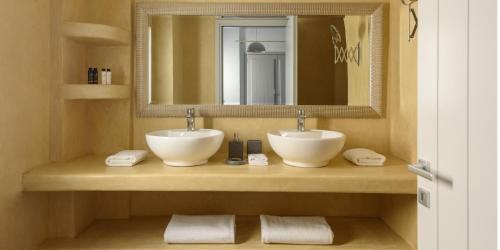 a bathroom with two sinks and a mirror and towels at Elitoz Suites in Oia