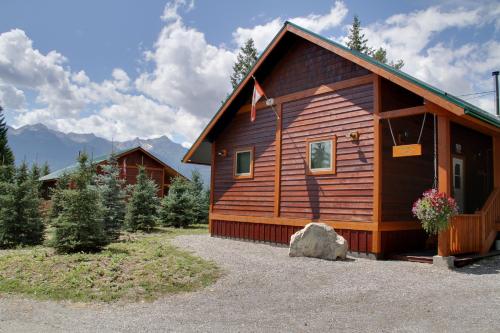 a cabin in the woods with a rock in front of it at Cedar House Restaurant & Chalets in Golden