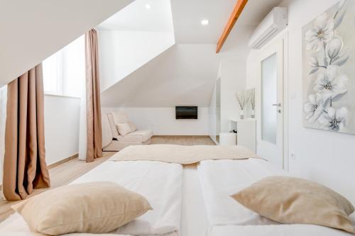 a white bedroom with two beds and a couch at Apartments Villa Tudor in Hvar