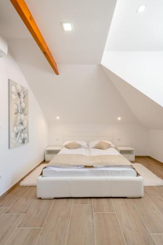 a bedroom with a white bed in a attic at Apartments Villa Tudor in Hvar