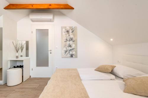 a white bedroom with a bed and a mirror at Apartments Villa Tudor in Hvar