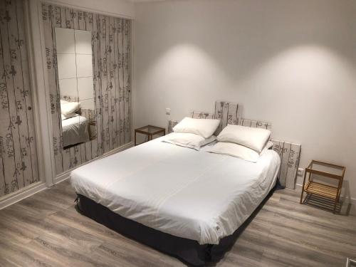 a bedroom with a large white bed and a mirror at Appartement port bonifacio in Bonifacio