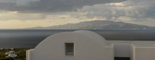 a white building with a view of the ocean and a mountain at Elitoz Suites in Oia