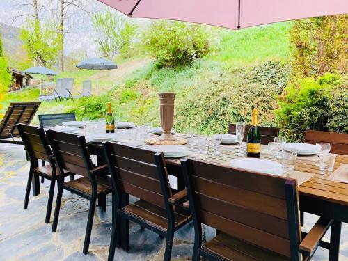 une table avec des chaises et un parasol sur une terrasse dans l'établissement Chalet Greystone, à Brides-les-Bains