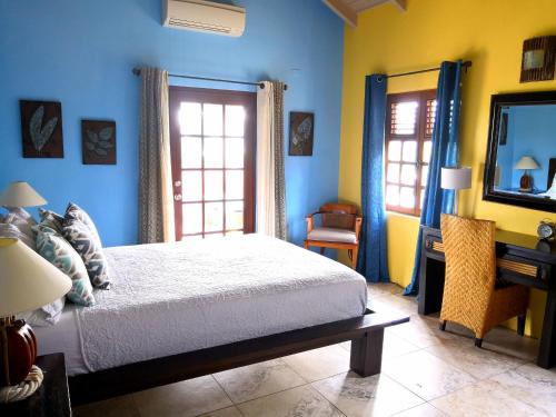 a bedroom with blue walls and a bed and a mirror at Villa Touloulou in English Harbour Town