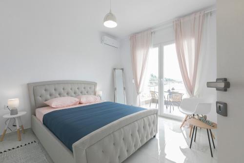 a white bedroom with a bed and a balcony at PORTO AZZURO SITHONIA GREECE in Neos Marmaras