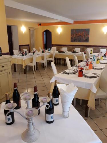 a restaurant with white tables and bottles of wine at Locanda della luna rossa in Calosso