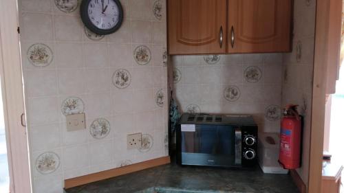 a kitchen with a microwave and a clock on the wall at 8 Berth Sealands (Highbury) in Ingoldmells