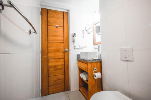a bathroom with a toilet and a wooden door at City Suites & Beach Hotel in Willemstad