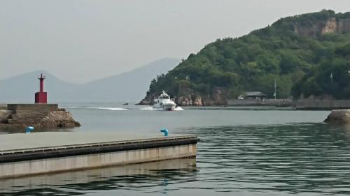 a boat in a body of water with a lighthouse at Guest House Shiraishi in Kasaoka