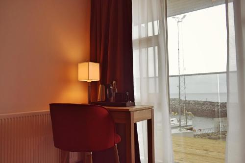 a desk with a lamp and a chair next to a window at Hotel Duus by Keflavik Airport in Keflavík