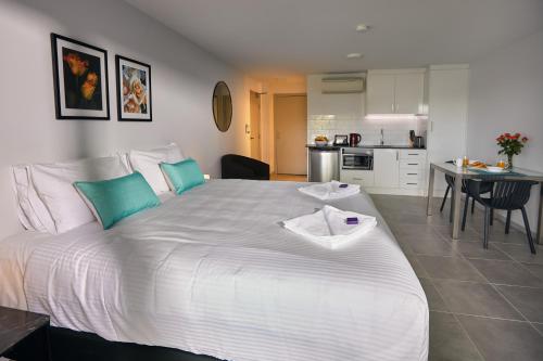 a large white bed in a room with a kitchen at East Maitland Executive Apartments in Maitland
