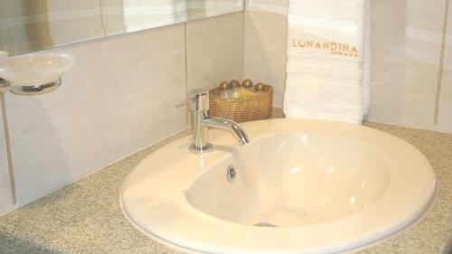 a bathroom sink with a faucet and a basket at Lunandina Huaraz in Huaraz
