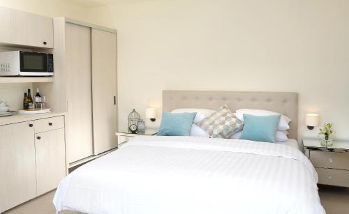 a white bedroom with a large white bed with blue pillows at Studio 8 - Penthouse in Melbourne