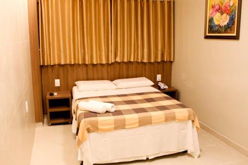 a bedroom with a bed with a checkered blanket at Vila Rica Hotel Caruaru in Caruaru