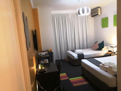 a hotel room with two beds and a desk at Criterion Hotel Perth in Perth
