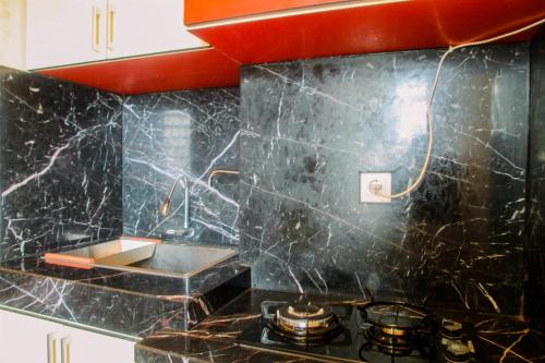 a kitchen with a black marble counter top and a stove at Luxury Furnished 2BR Grand Kamala Lagoon Apartment By Travelio in Pulosirih
