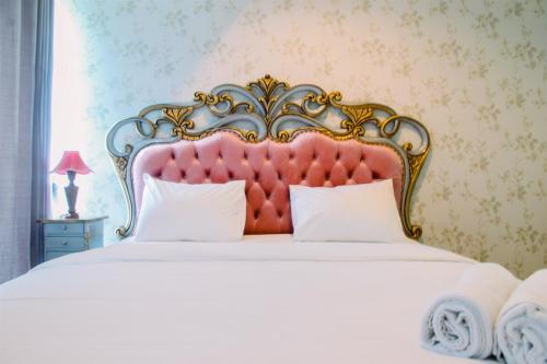 a bedroom with a large bed with a red headboard at Luxury Furnished 2BR Grand Kamala Lagoon Apartment By Travelio in Pulosirih