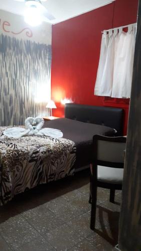 a bedroom with a bed and a chair and red walls at Hotel Florencia in Necochea