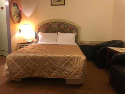 a bed in a hotel room with a couch and a chair at 真正好旅店 Good Hotel in Fengyuan