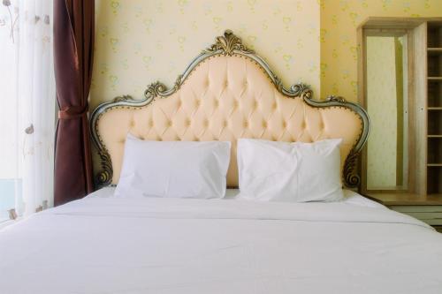 - une chambre avec un lit blanc et une grande tête de lit dans l'établissement Vintage 2BR Apartment at Grand Kamala Lagoon By Travelio, à Pulosirih