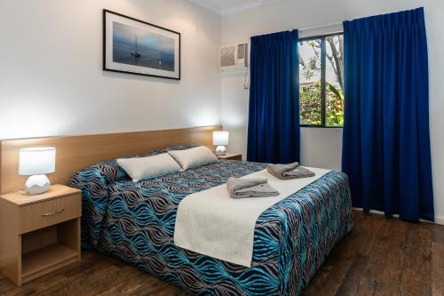 una camera da letto con un letto con tende blu e una finestra di Broome Beach Resort - Cable Beach, Broome a Broome