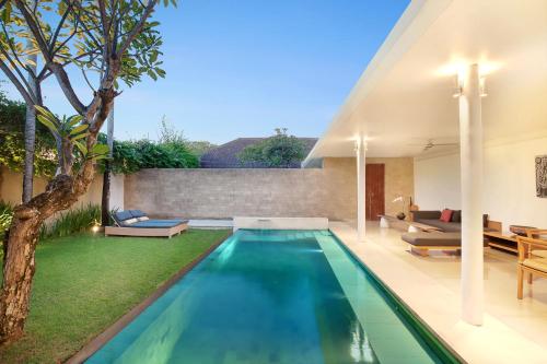 an infinity pool in a backyard with a house at Uma Sapna Seminyak in Seminyak