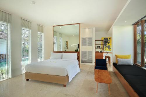a bedroom with a large white bed and a mirror at Uma Sapna Seminyak in Seminyak