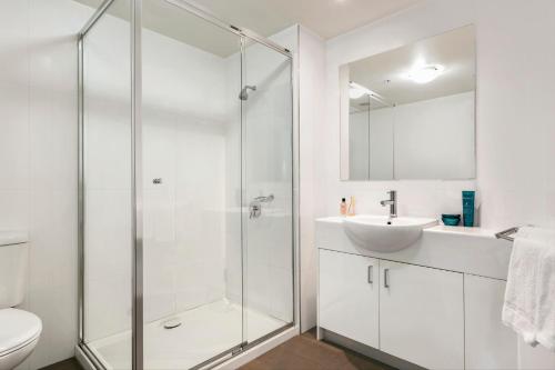 a white bathroom with a shower and a sink at Quest Cheltenham in Cheltenham