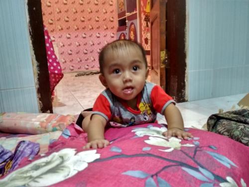 a baby sitting on the floor on a pink blanket at Homestay Buang Sari in Gresik