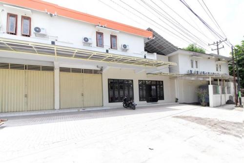 a white house with a motorcycle parked in front of it at RedDoorz near Jogja Kembali Monument 3 in Kalasan