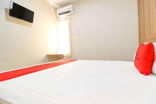 a bedroom with a white bed with a red pillow at RedDoorz near Jogja Kembali Monument 3 in Kalasan