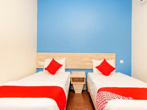 2 camas en una habitación con almohadas rojas en OYO 778 Bmw 2 Hotel, en Muar
