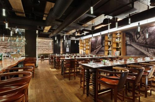 a restaurant with wooden tables and chairs and a brick wall at Andaz 5th Avenue, By Hyatt in New York