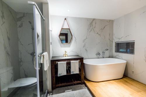 a bathroom with a white tub and a shower at The Western Clouds in Deqing