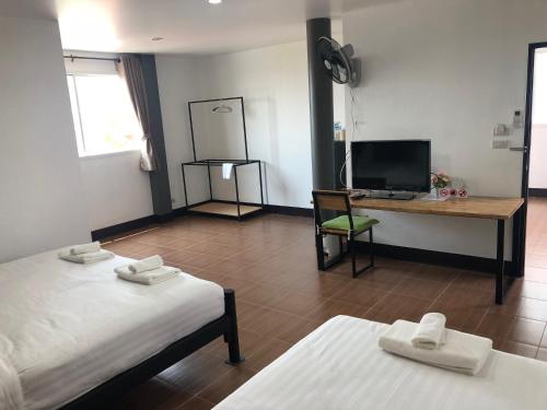 a room with two beds and a desk and a television at Khaohom House in Chiang Mai