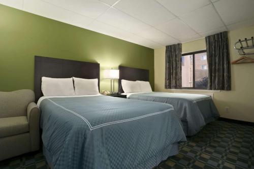 a hotel room with two beds and a couch at Travelodge by Wyndham Cleveland Lakewood in Lakewood