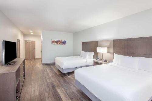 a hotel room with two beds and a flat screen tv at La Quinta by Wyndham Dallas Duncanville in Duncanville